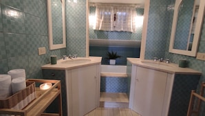 A bathroom with two sinks, a mirror, a towel rack, and a small plant.