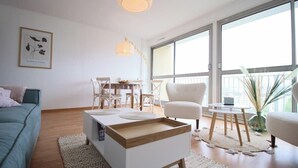 Ein modernes Wohnzimmer mit Sofa, Couchtisch und einem Essbereich mit Stühlen und Tisch.