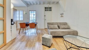 A compact living space with a dining area, a sofa, and a glass coffee table. - Damien, votre *F3 *2 chambres *terrasse à *Rouen (Rouen)