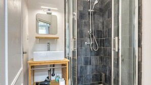 A modern bathroom with a glass-enclosed shower, a white sink, and a wooden vanity.