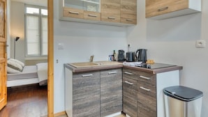 A compact kitchen with wooden cabinets, a sink, and a coffee machine.