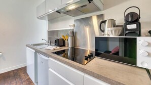 Una cocina moderna con una campana extractora de acero inoxidable, un microondas y un hervidor sobre la encimera.