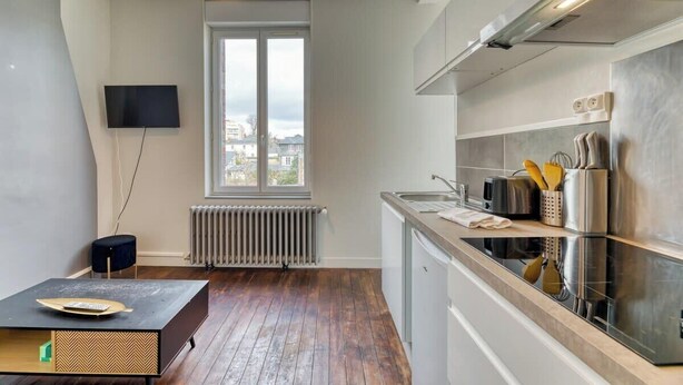 Una cocina moderna con un amplio ventanal, horno empotrado y encimera con utensilios de cocina.