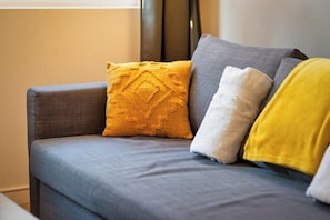 Relax on the sofa with three plush cushions, including a yellow one with a textured design.
