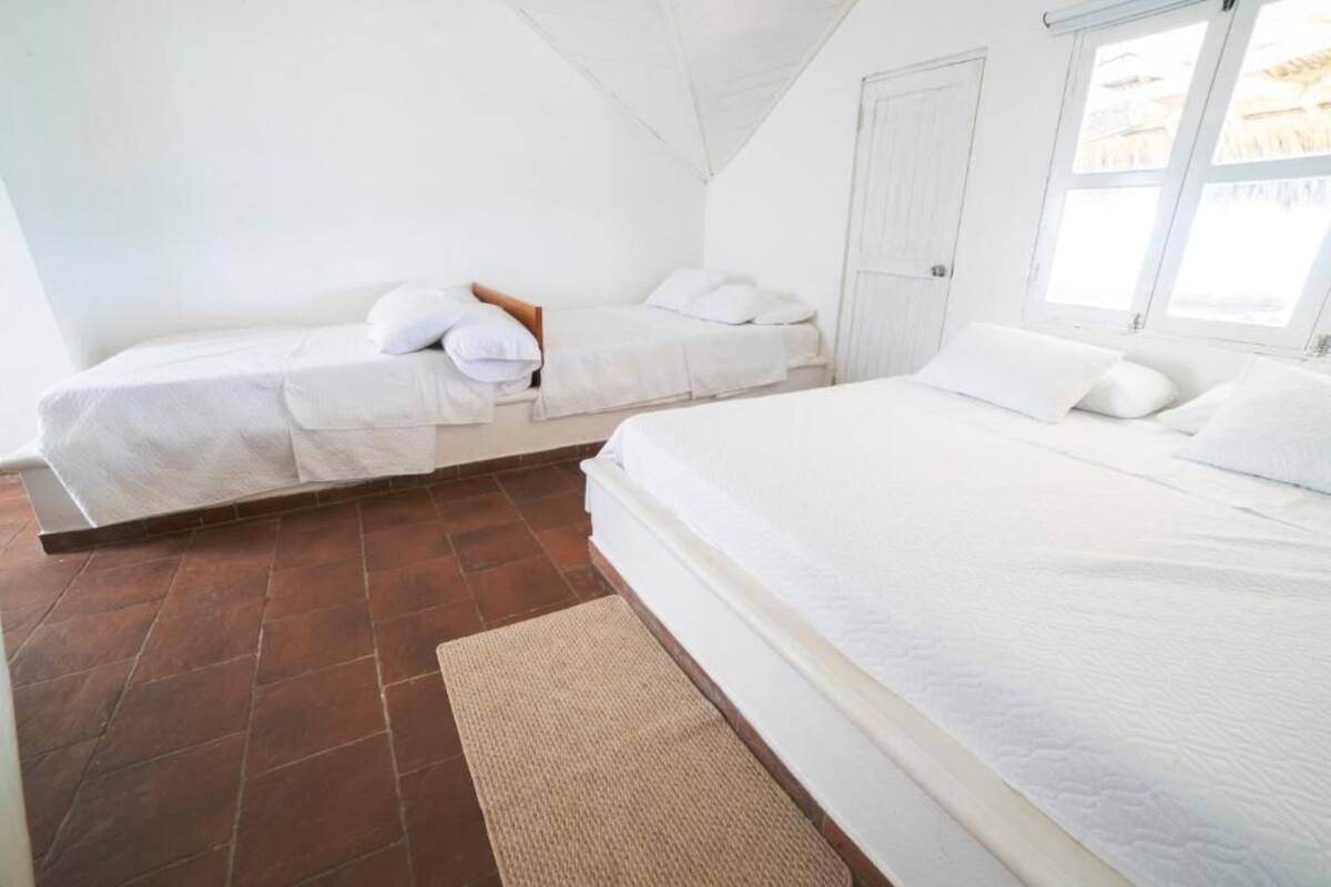A bedroom with two beds, a wooden door, and a window.