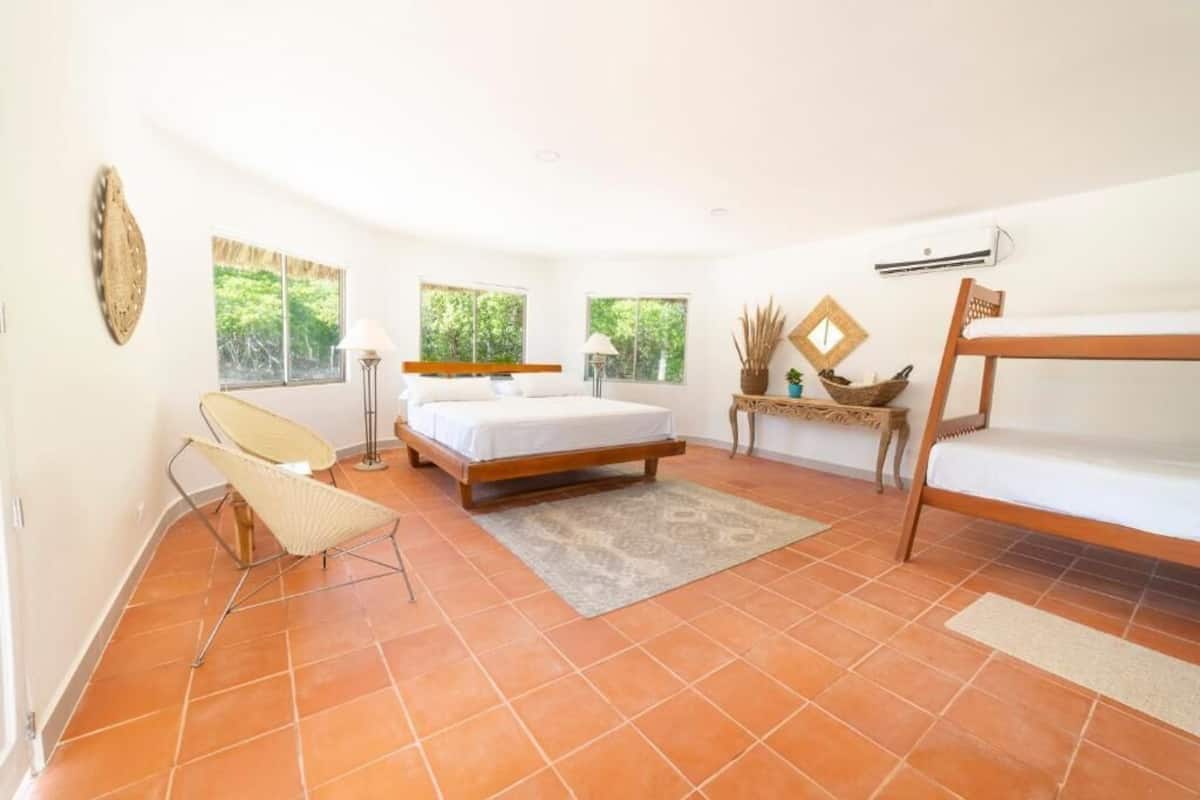 A bedroom with a bed, a chair, a bedside table, and a window.