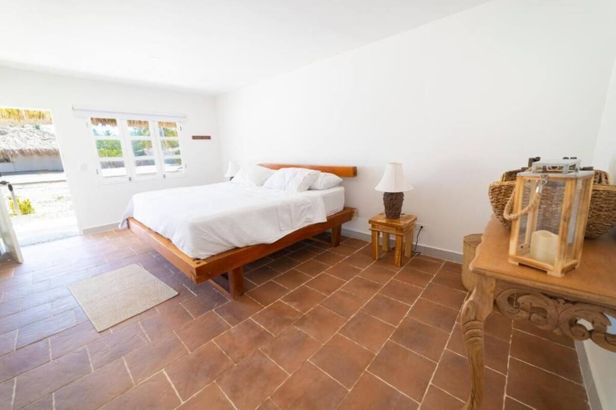 A bedroom with a wooden bed, a small bedside table with a lamp, and a wicker basket.