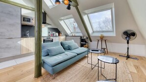 Een modern loft appartement met een hoogslaper, een bank, een kleine tafel en een ventilator.