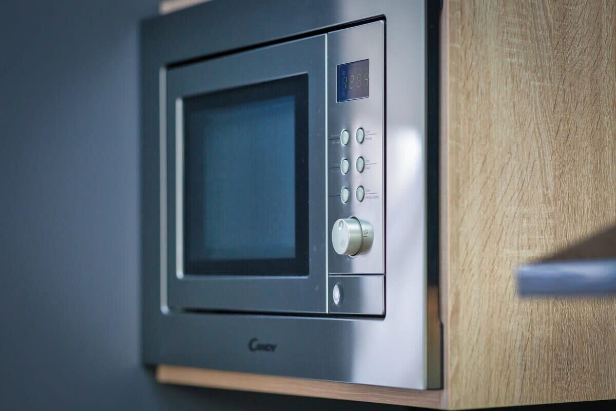 A microwave with a digital display and control buttons, placed in a kitchen setting.