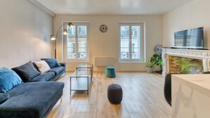 Un salon moderne comprenant un canapé, une table basse, un pouf rond, une cheminée et un téléviseur.