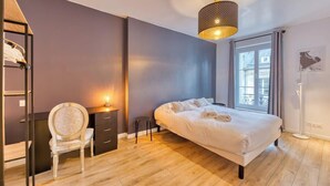 Une chambre à coucher avec un lit, une chaise, un bureau, une lampe et une fenêtre.
