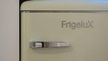 A vintage FrigeluX refrigerator in a kitchen with a tiled backsplash and a wooden countertop.