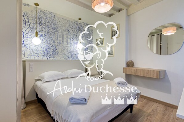 Un dormitorio con cama, mesita de noche y pared con estampado floral azul.