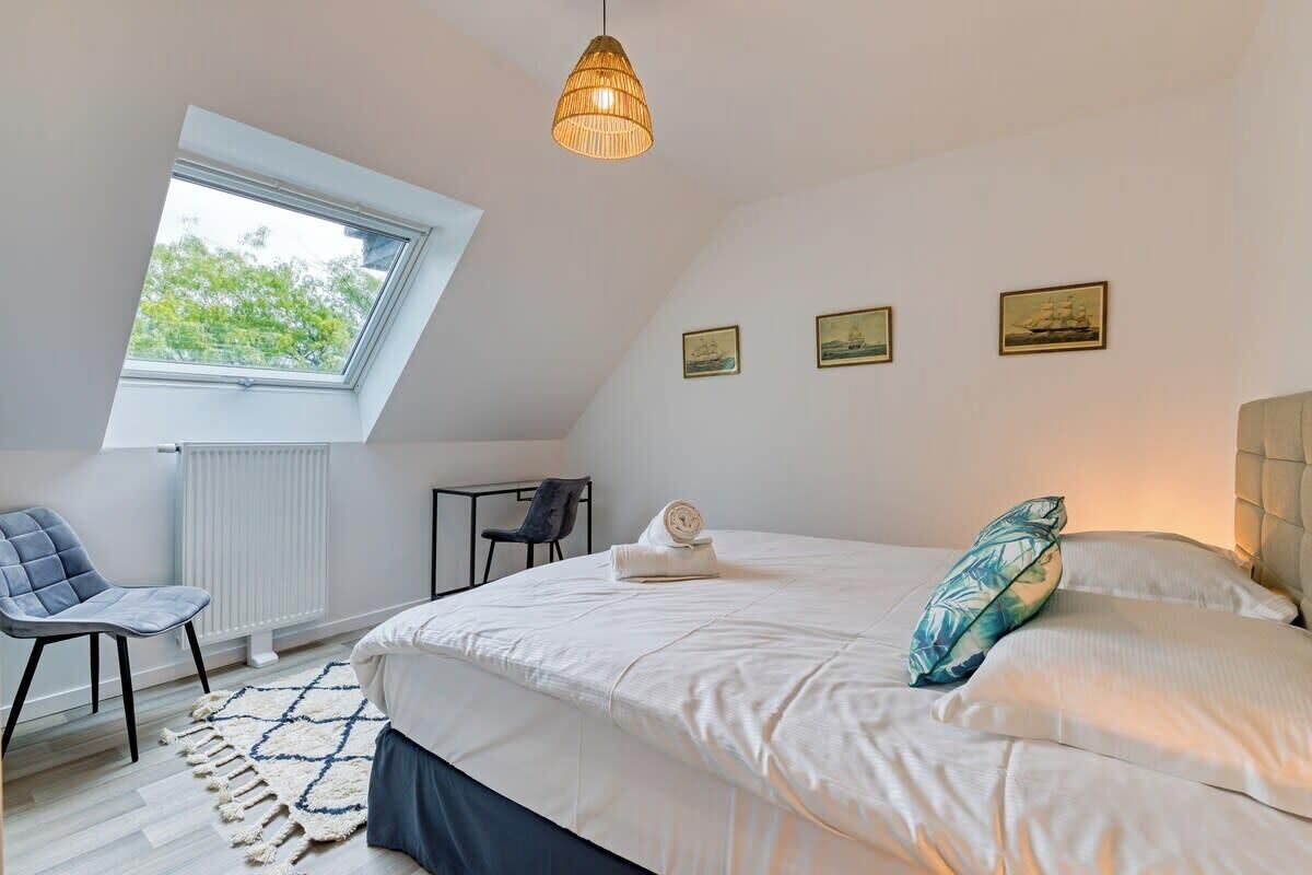 Une chambre à coucher avec un grand lit, une lucarne, un bureau et une chaise.