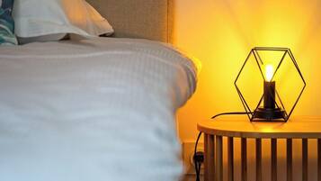 A neatly made bed with a headboard, a bedside lamp, and a pillow.
