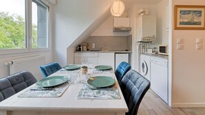 A modern kitchen with a dining area, including a table set for four with green plates and a pendant light. - Solent, joli F2 proche Jardin des Plantes à Rouen (Rouen)