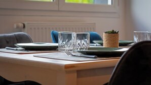 A dining table set with plates, cutlery, and glasses, with a woven basket and a plant on the table. - Solent, joli F2 proche Jardin des Plantes à Rouen (Rouen)