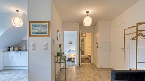 A modern apartment with a kitchen, dining area, and living room. There are pendant lights, a painting, and a wooden rack. - Solent, joli F2 proche Jardin des Plantes à Rouen (Rouen)