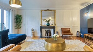 A living room with a blue sofa, a round gold coffee table, a fireplace, and a large mirror.
