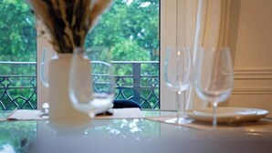 A dining table with a vase of dried flowers, a wine glass, and a plate.