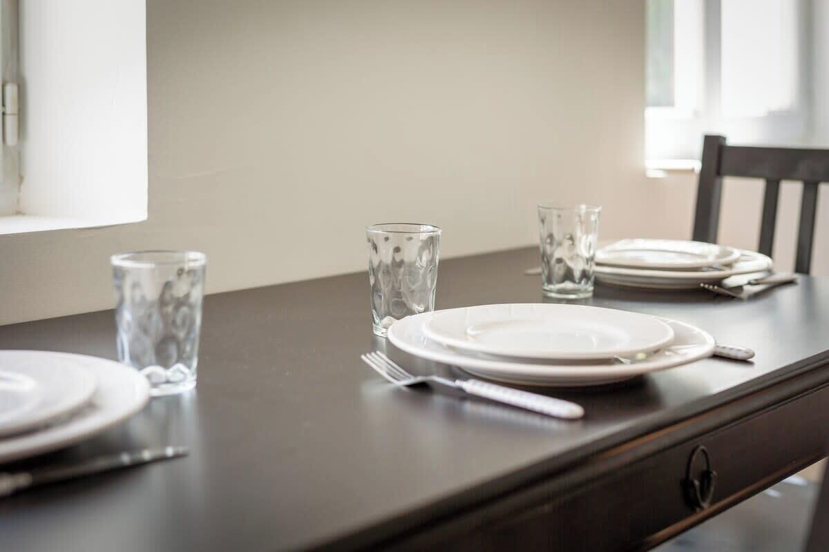 Una mesa de comedor dispuesta con platos, vasos y cubiertos.
