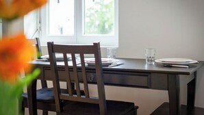 A dining table with chairs, a window, and a vase of flowers. - Rollin, appartement 3 personnes avec Netflix au calme ! (Sotteville-lès-Rouen)