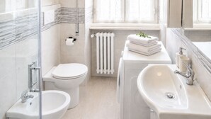 Un bagno moderno dotato di wc, bidet, lavandino e termosifone.