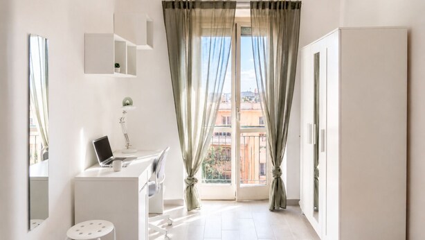 Una camera da letto moderna con una scrivania, una sedia, un piccolo sgabello e un letto.