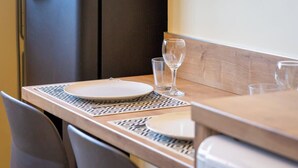 Una mesa de comedor con un posavasos estampado, un plato blanco y una copa de vino.