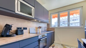 Una cocina compacta con microondas, cafetera y horno empotrado.
