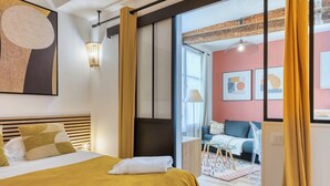 Une chambre d’hôtel moderne dotée d’un grand lit, donnant sur un balcon, et présentant un design intérieur contemporain.