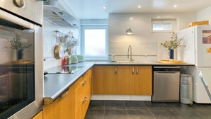 A modern kitchen with a dishwasher, oven, and a window providing natural light.
