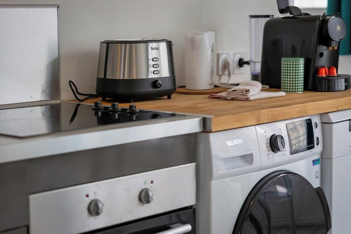 Et tekøkken med en Tefal-toaster, kaffemaskine, vaskemaskine og mikrobølgeovn.