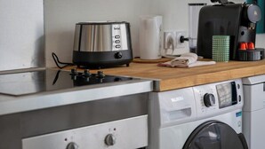 Una kitchenette equipada con un tostador Tefal, una cafetera, una lavadora y un microondas.