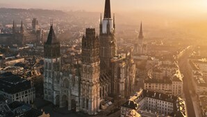 Una catedral con una aguja alta, rodeada de edificios históricos y un río.