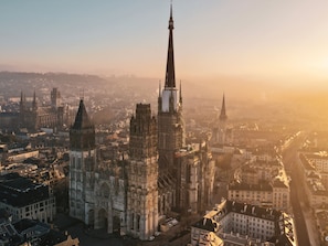 A cathedral with a tall spire, surrounded by historic buildings and a river.