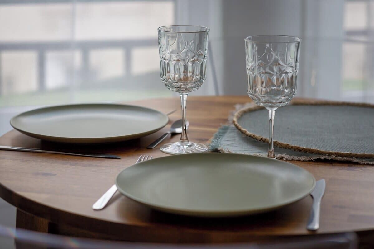 A dining table with two clear glassware items, a plate, and cutlery.