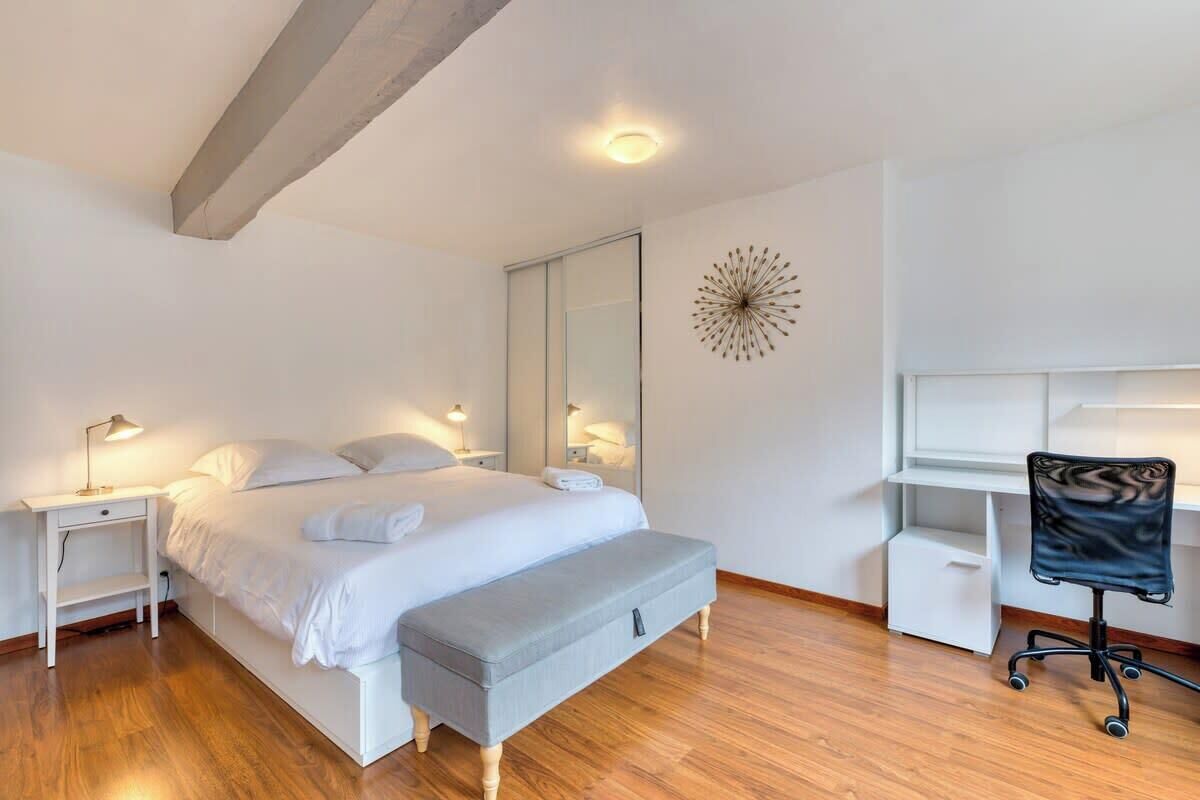 A modern bedroom with a bed, bedside tables, a desk, and a chair.