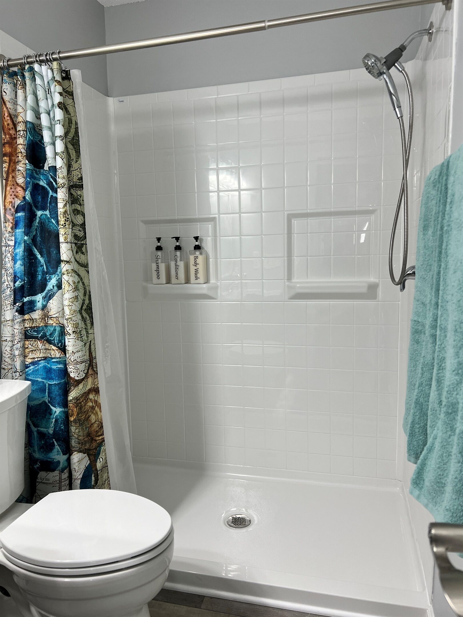 A bathroom with a shower, toilet, and a shelf with toiletries.