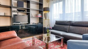 A modern living room with a sofa, a coffee table, a TV, and a bookshelf.