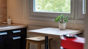 A kitchen with a wooden countertop, a small stool, a potted plant, and a red appliance.