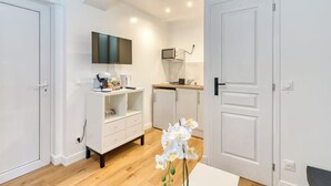Una cocina compacta con armarios blancos, microondas y cafetera.