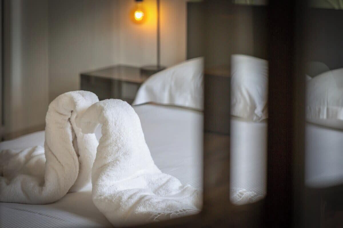 A neatly made bed with white linens, a bedside table, and a lamp in a hotel room.
