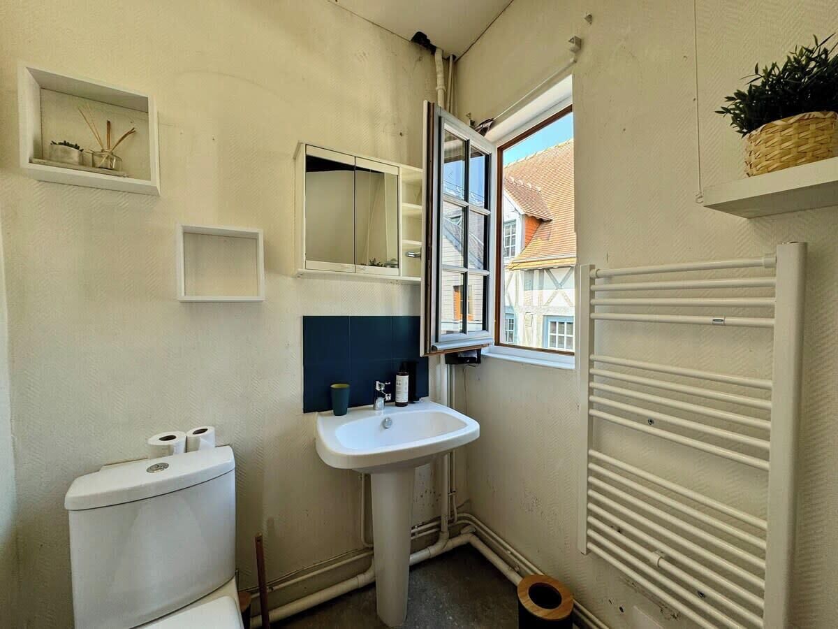 Une petite salle de bain compacte, équipée de toilettes, d’un lavabo et d’une fenêtre.