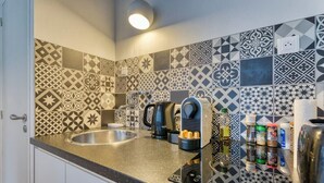 A kitchen with a granite countertop, a kettle, a coffee maker, and various condiments.