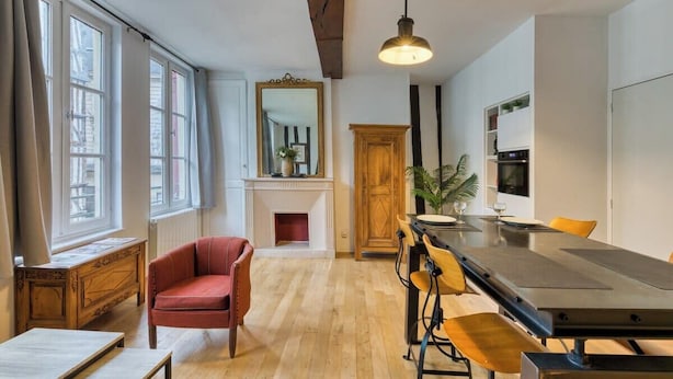 A modern kitchen with a dining table, chairs, a fireplace, and large windows.