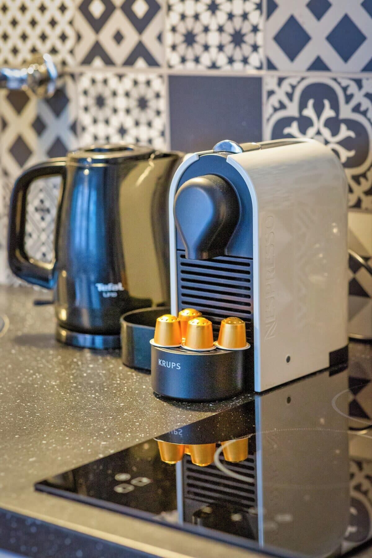 Eine Kaffeemaschine mit vier Kaffeekapseln auf einer Küchenarbeitsplatte.