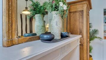 A white mantelpiece with three vases, a mirror, and a wooden cabinet.