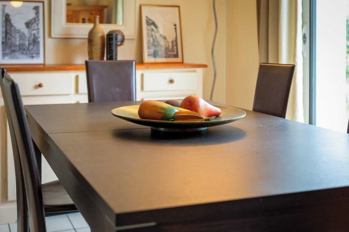 A dining table with a plate of fruit and a vase.