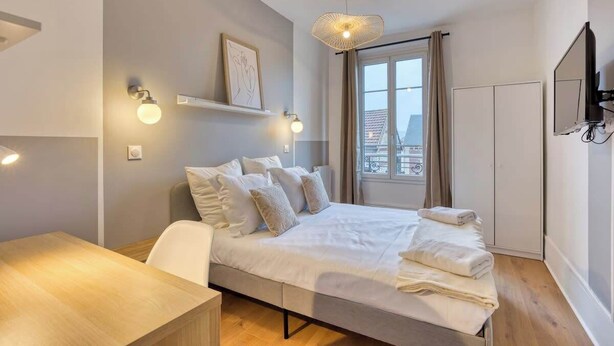 A modern bedroom with a bed, bedside table, and a large window.